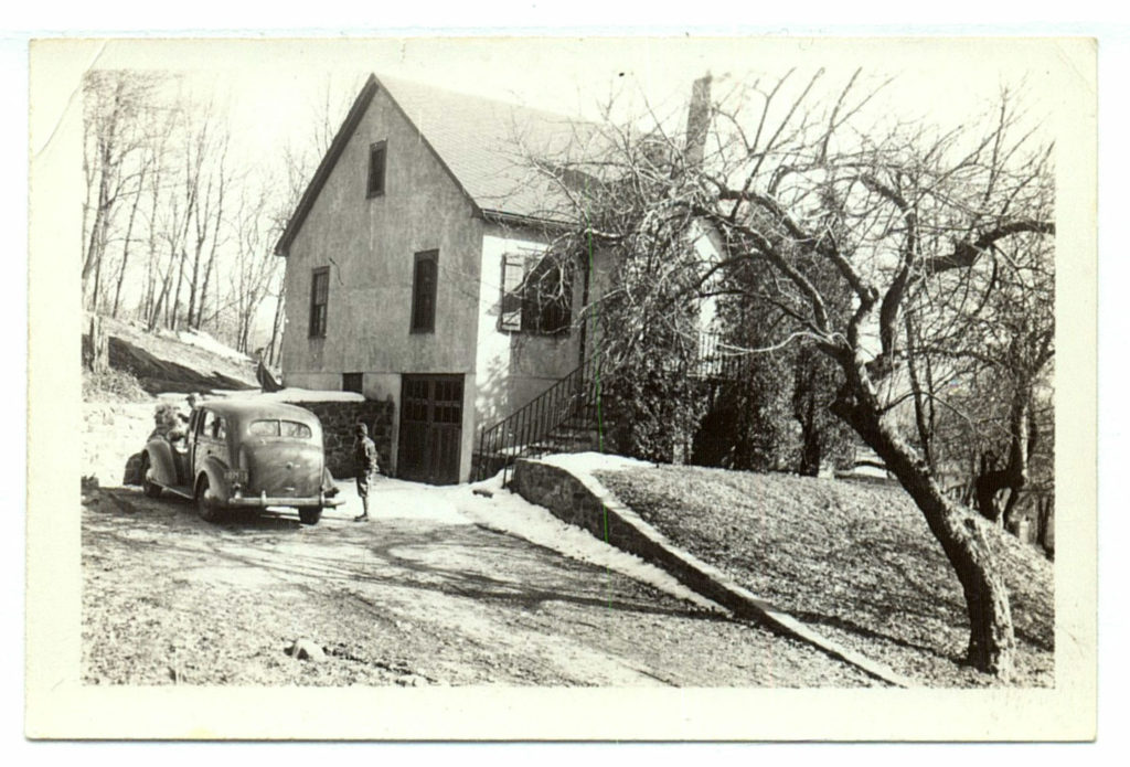 A black and white vintage photo of a little cottage in the woods.