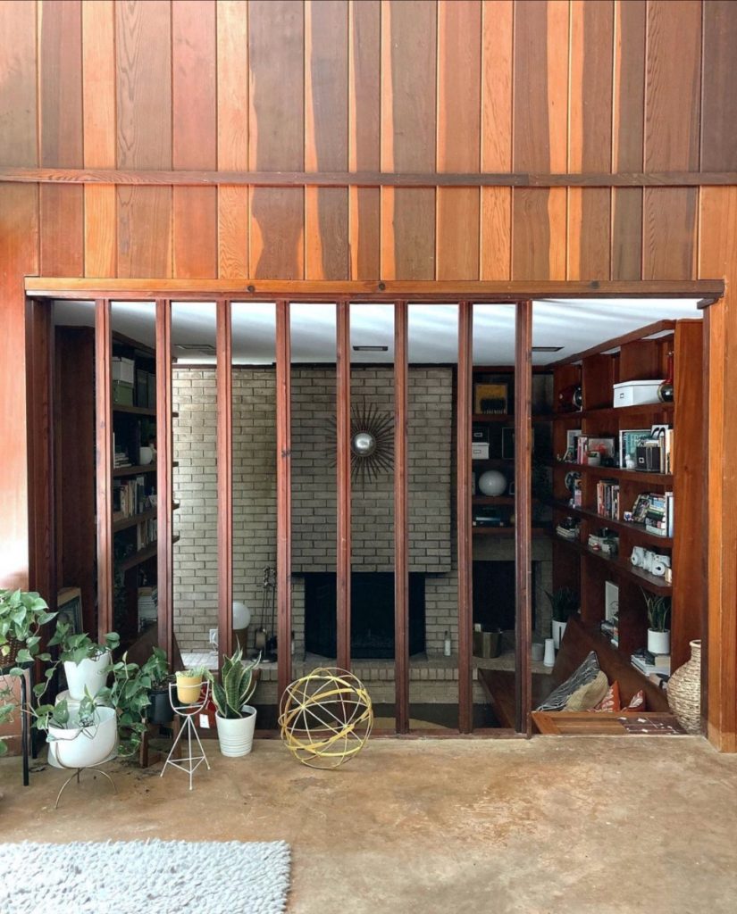 A view of the living room from another angle, through an mezzanine area. There is beautiful, dark wood panel on the walls.