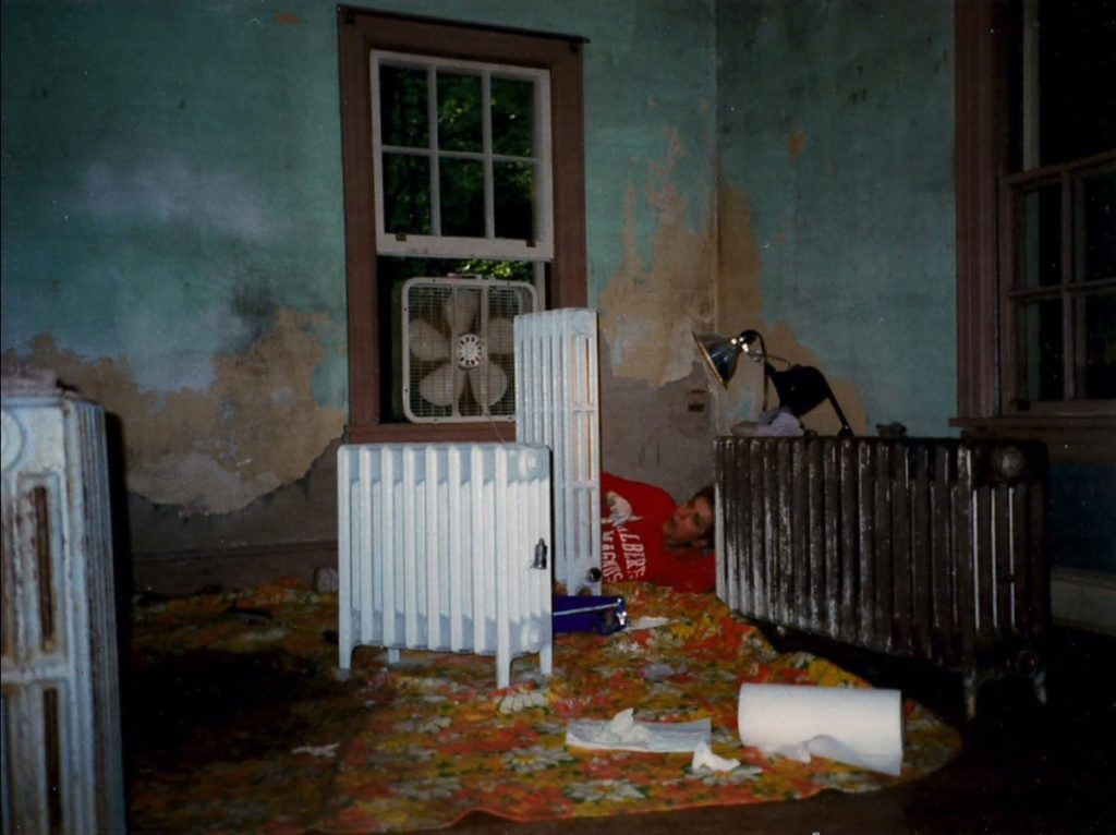 A creepy photo of a room inside an old cottage with multiple antique radiators in it.