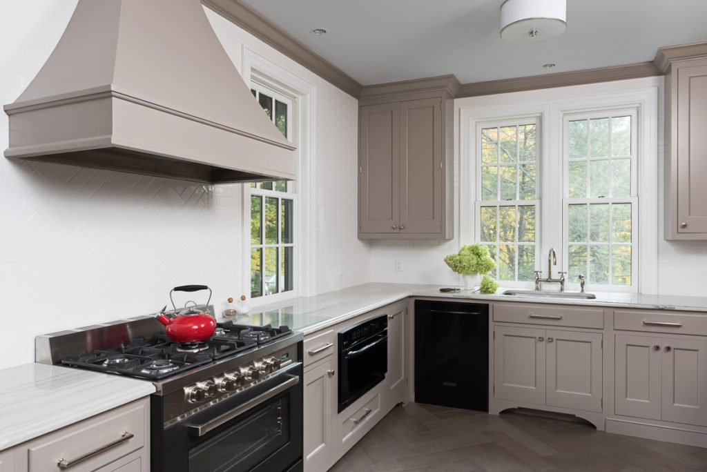 An updated kitchen in an old cottage, with gray trim and white walls and a high-end gas stove.