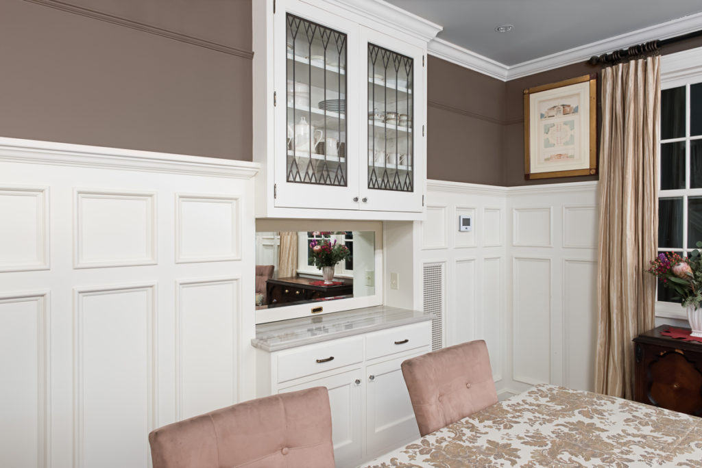 A  photo of a dining room with high white panels on the walls.