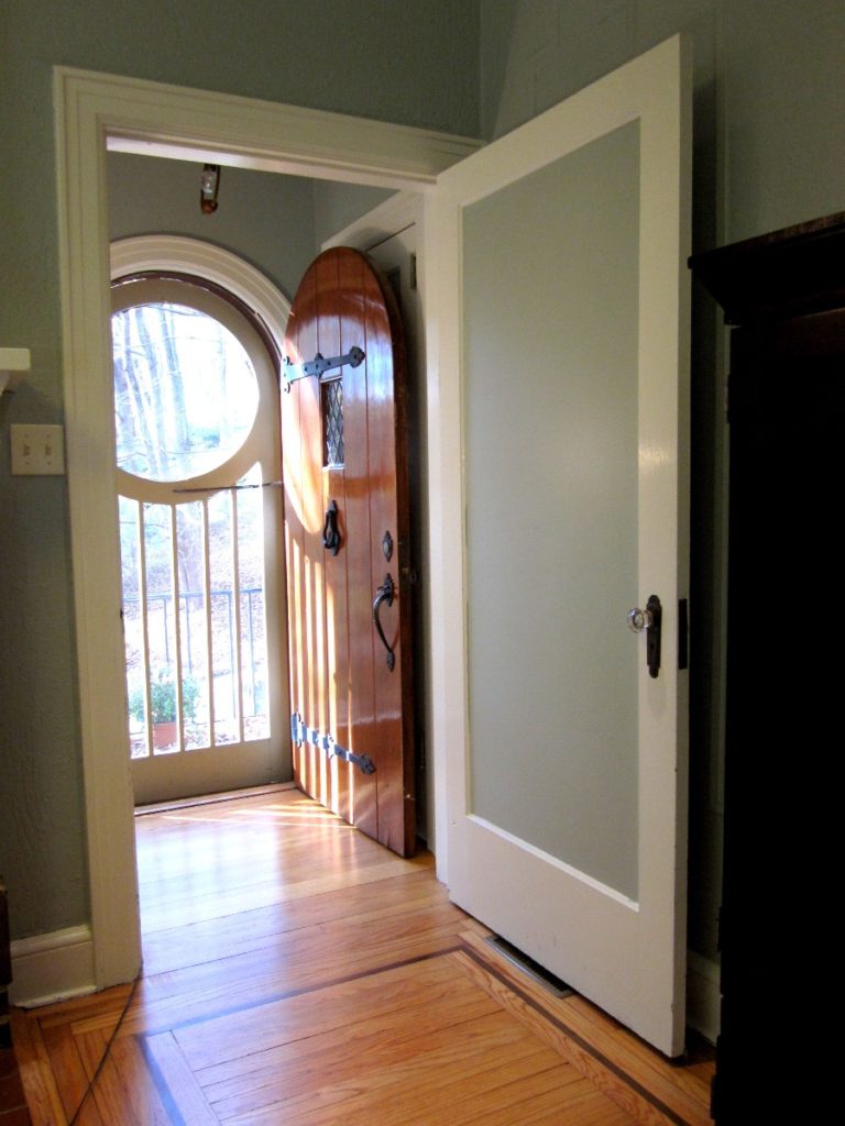 A photo of the front door of the cottage from inside. The door is open, revealing a strikingly geometric custom screen door.