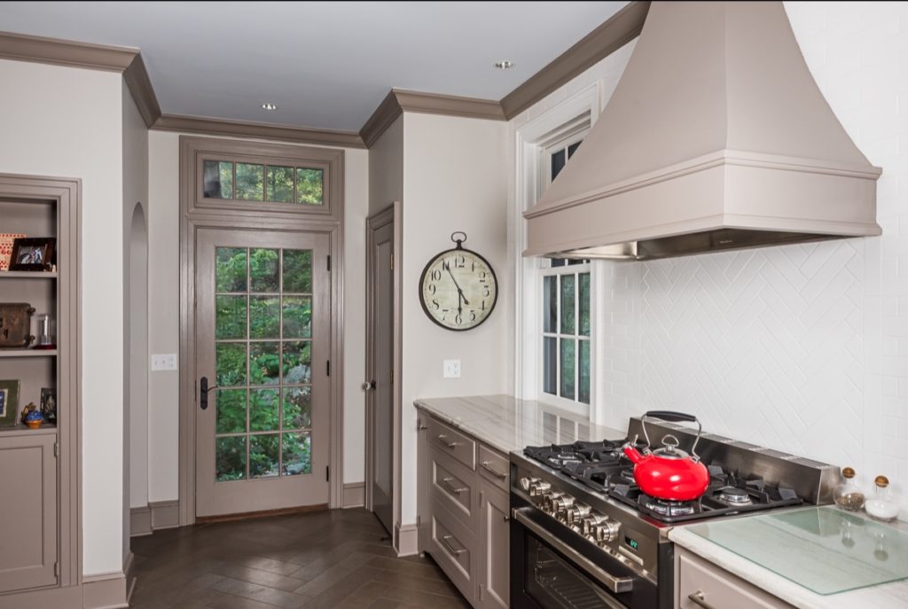 An updated kitchen in an old cottage, with gray trim and white walls and a high-end gas stove.