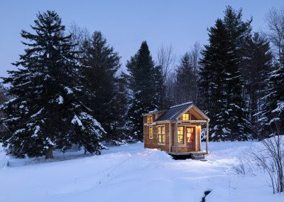 A tiny wooden house in the woods in the winter, the result of a tiny home renovation.