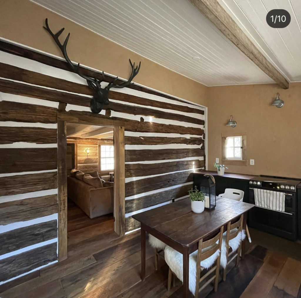 The dining room of the log cabin after renovation, with a big deer head over the door.