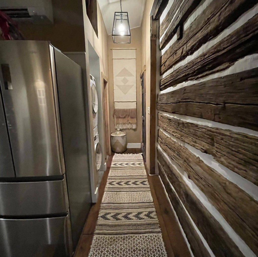 A view of the hallway in the log cabin, with a geometric patterned runner rug.