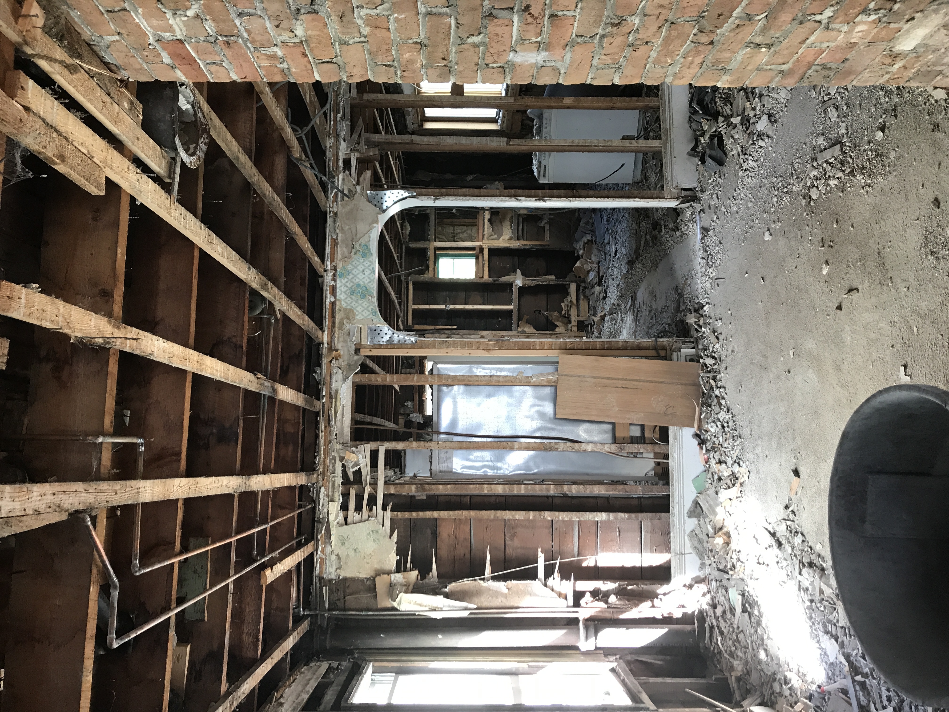 A house during a gut renovation, stripped down to the framing. A brick chimney is visible in the corner.