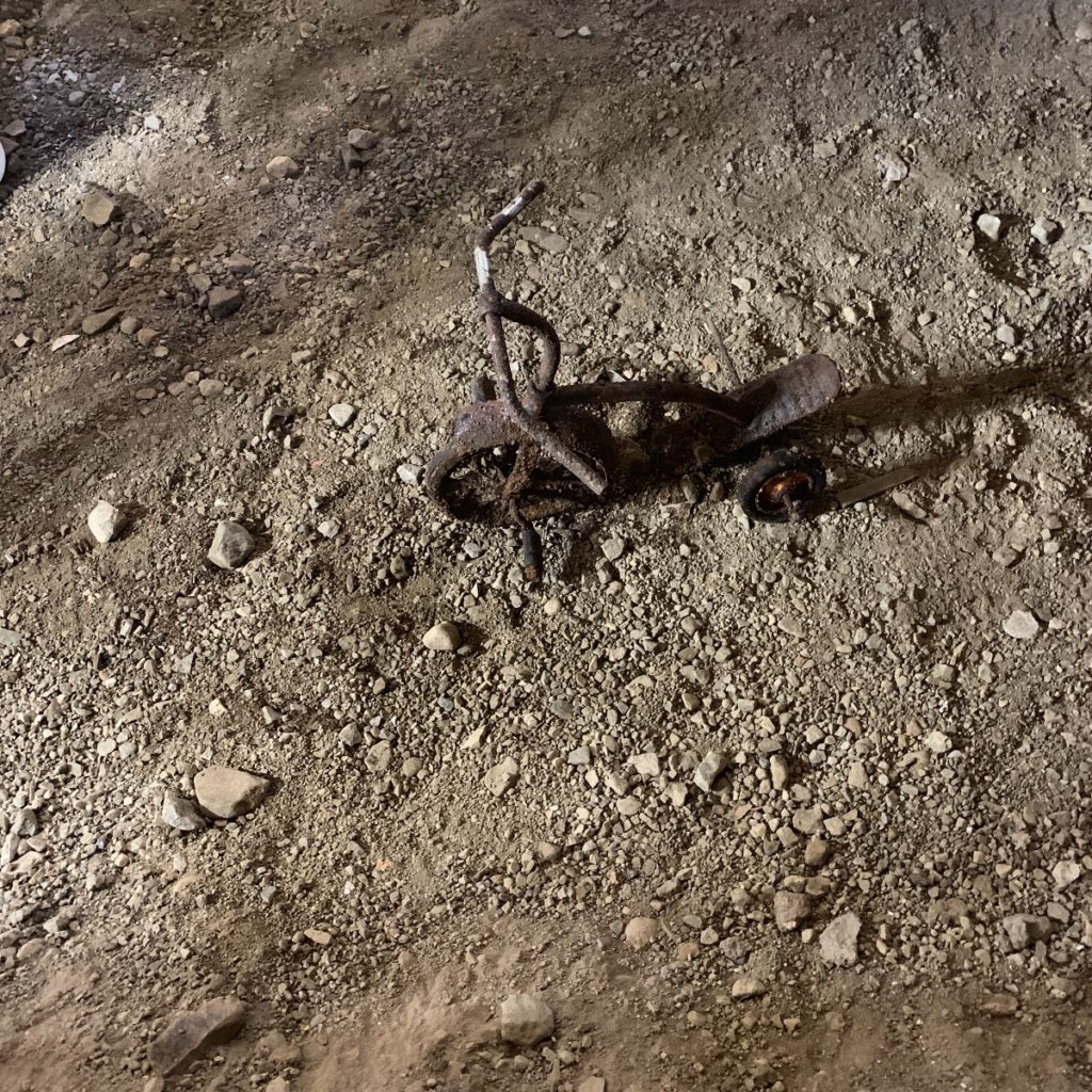 A dirty floor during a renovation with a metal object on it.