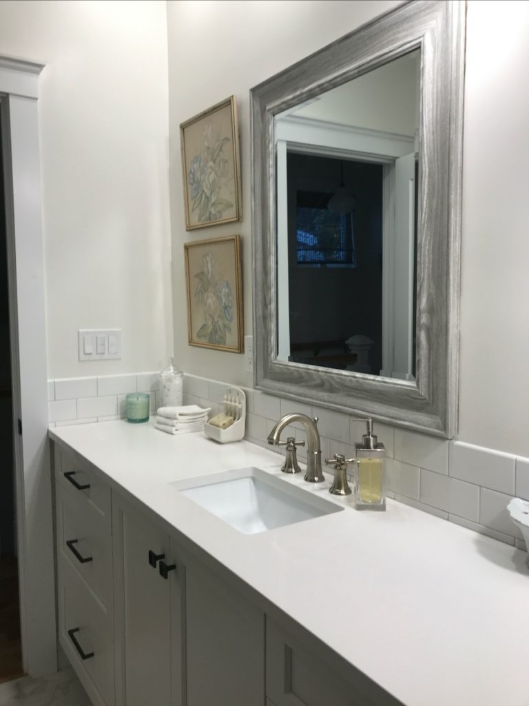 A white bathroom with a big picture mirror. 