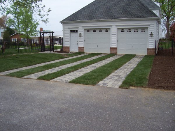 A two-car garage with four tracks of pavers with strips of grass in between.