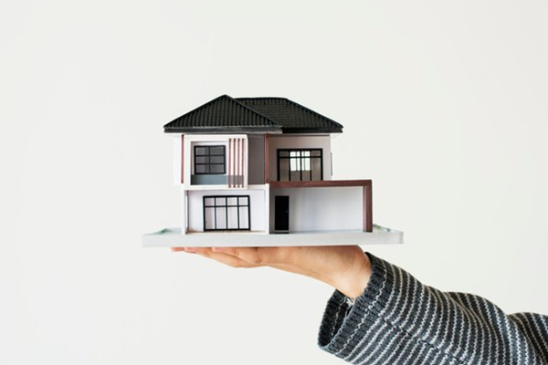 A hand holding up a small model of a house