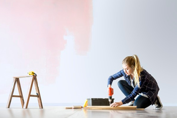 A woman holding a drill, working on a home renovation.